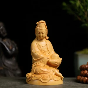 Front view of a golden boxwood Guanyin at Ease statue with both hands around a raised knee