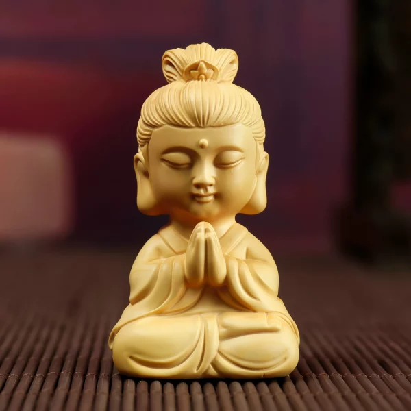 Mini boxwood Guanyin with joined palms, a rounded face and crossed legs, viewed from the front