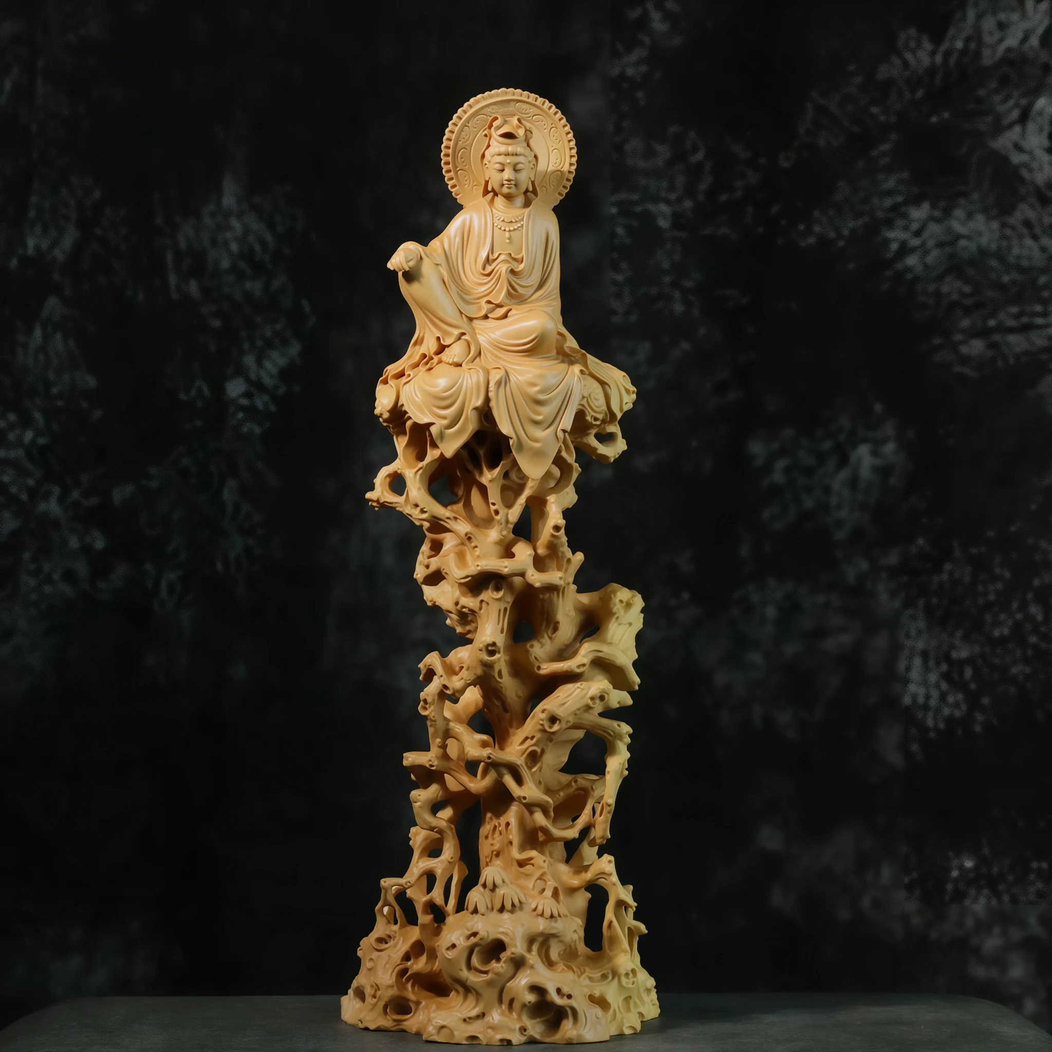 Front view of a boxwood Guanyin in royal ease above a tall openwork rock formation