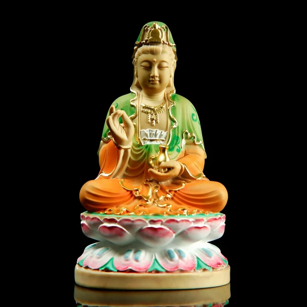 Painted boxwood Guanyin seated on a pink and white lotus base, with green and orange robes