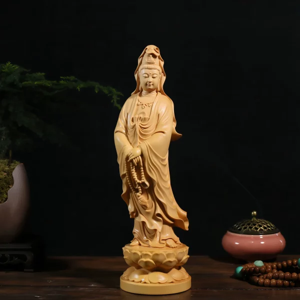 Front view of a golden boxwood Guanyin statue holding prayer beads above a double lotus pedestal
