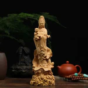 Front view of the boxwood Guanyin holding a smiling child above a lotus and wave base