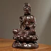 Three-quarter view of heitan wood Guanyin with a raised right hand and lotus pedestal