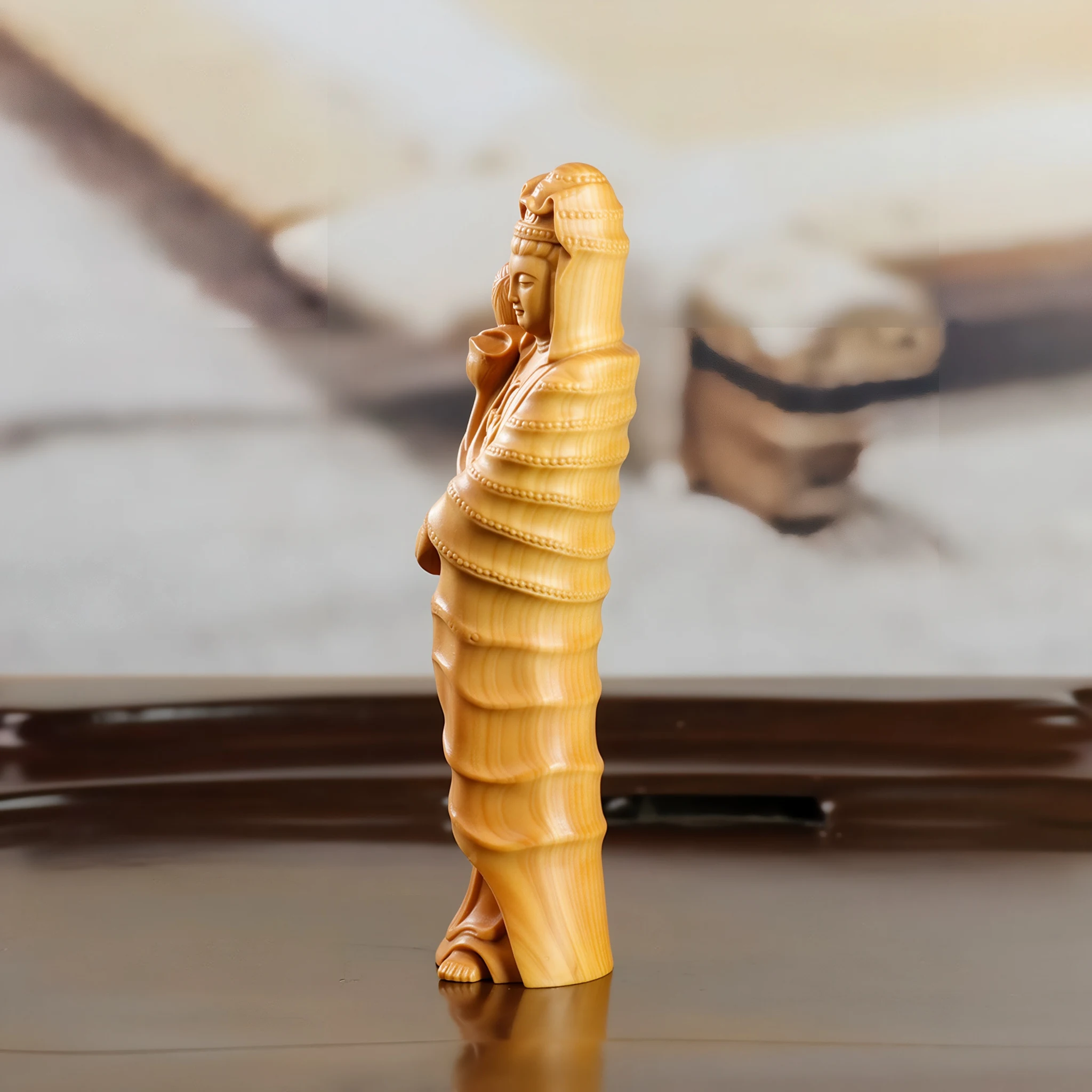 Side profile of the boxwood Guanyin, showing the layered bamboo-like folds of the robe