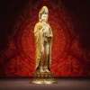 Three-quarter view of antique tea-gold Kuan Yin with a Dharma wheel and long flowing robes