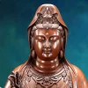 Close view of Guanyin’s lowered eyes and the small seated figure in the crown