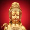 Face of the 38 cm brass Guanyin with lowered eyes, a red brow accent and a small Buddha in the crown