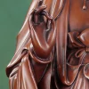 Close view of Willow Guanyin’s raised fingers holding the slender sprig against the copper robe