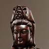 Close-up of Guanyin’s face and carved crown in dark brown wood