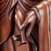 Kuan Yin’s left hand holding a narrow-necked vase tilted downward beside the copper drapery