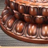 Rounded copper lotus petals with darker recesses on the seated Guanyin pedestal