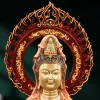 Close view of the coral and gold Guanyin’s face, small seated crown figure and openwork flame halo