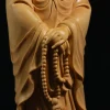 Carved hands holding a loop of prayer beads against the flowing robes of Nazhu Kuan Yin