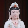 Close-up of the Baoxiang Guanyin statue with painted eyes, a gentle smile and a small seated figure in the turquoise crown detail