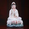 Three-quarter view of the Baoxiang Kuan Yin statue, showing the raised hand, gold-tone vase and layered white robes above the lotus base