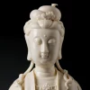 Chijing Kuan Yin’s lowered eyes, forehead dot and high hair bun in glossy ivory porcelain