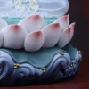 Pink-tipped lotus petals, teal leaves and curling dark blue waves beneath the Cilian Guanyin statue