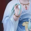 Close-up of Kuan Yin’s raised fingers holding a green willow branch beside the pale blue sleeve