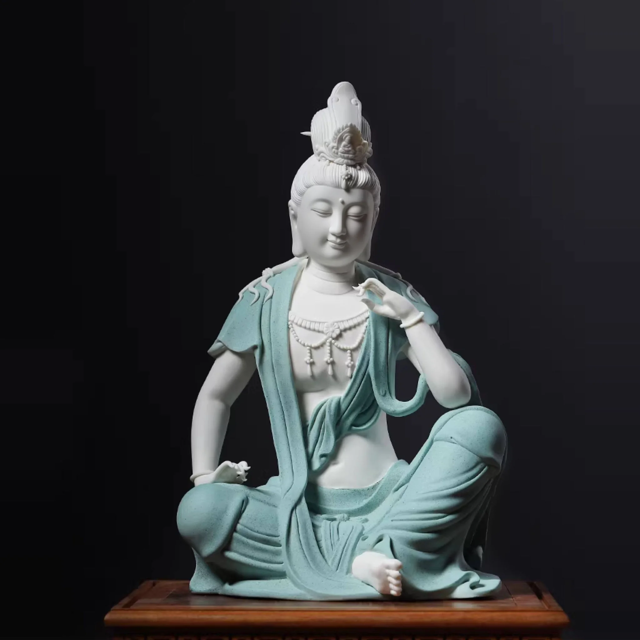 Front view of the contemplative Guanyin statue with one knee raised, a lifted hand and textured teal robes, 33 cm (13.0 in) tall