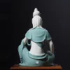 Back view of the contemplative Guanyin statue showing sculpted hair, the teal shawl around the shoulders and an impressed mark