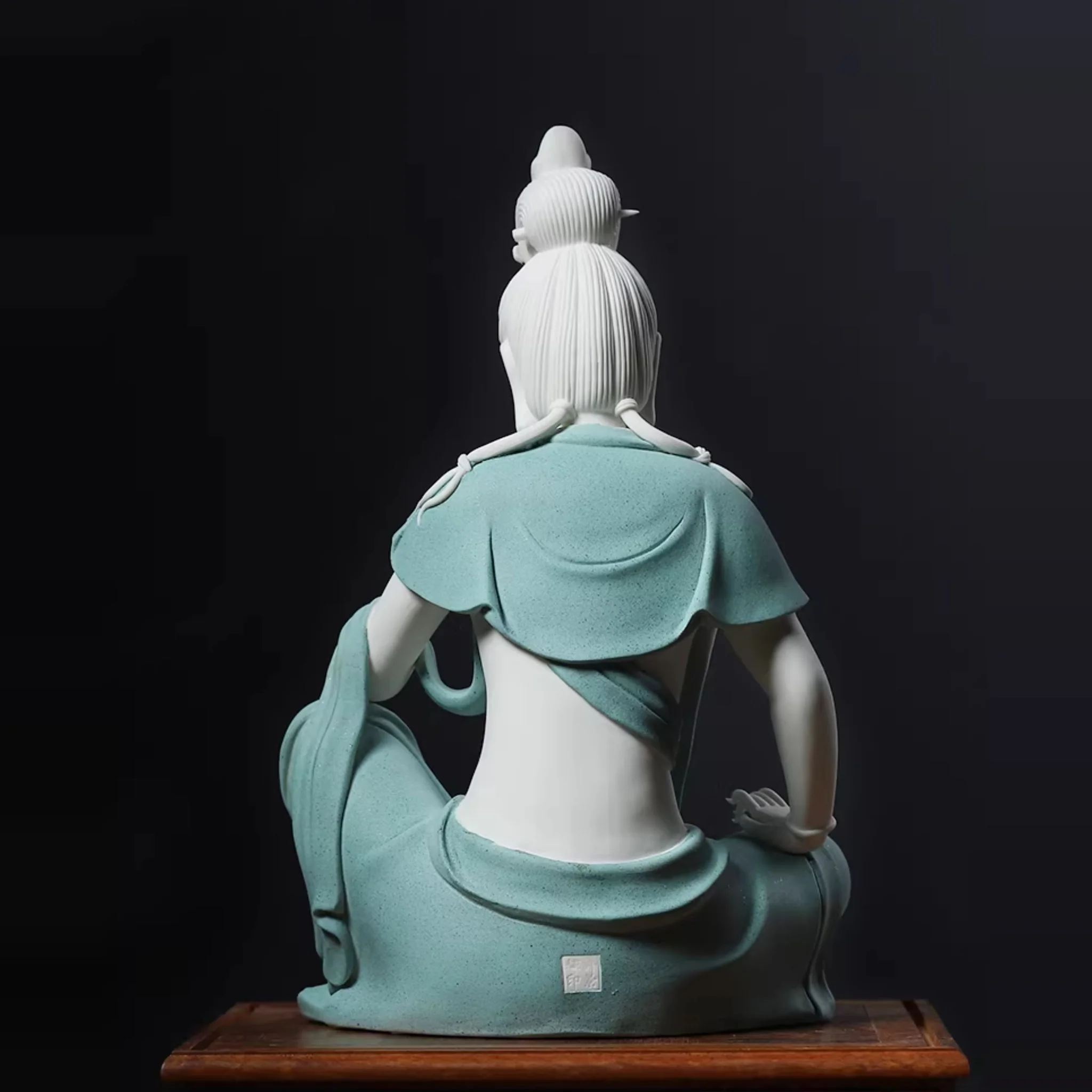 Back view of the contemplative Guanyin statue showing sculpted hair, the teal shawl around the shoulders and an impressed mark