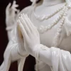 Joined palms and glossy sleeve folds of the white porcelain Four-Armed Guanyin