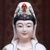 Smiling face, painted eyes and ornate crown of a white and purple Guanyin statue