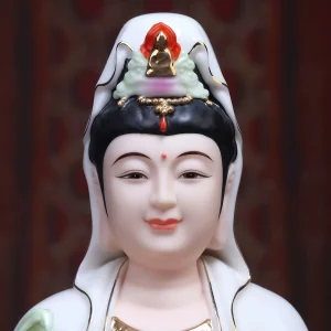 Smiling face, painted eyes and ornate crown of a white and purple Guanyin statue