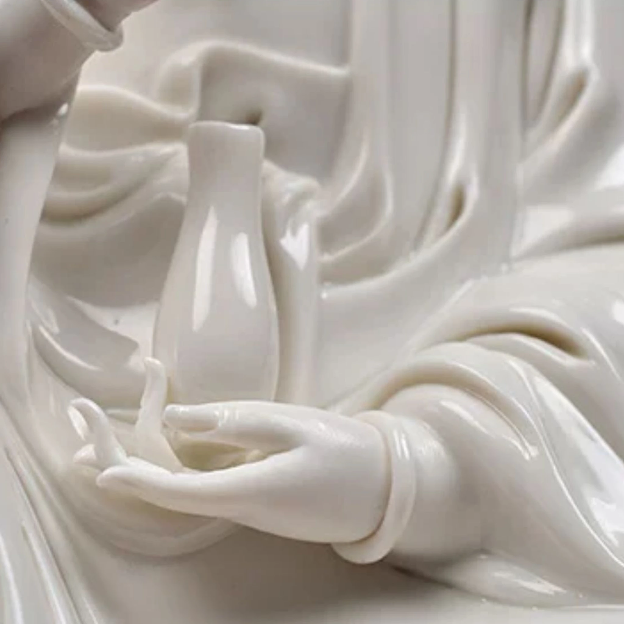 Lower hand of the Kuan Yin statue supporting a slender upright vase, beside the flowing sleeve