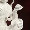 White porcelain Guanyin’s open palm supporting a lotus flower beside curling ribbons and draped sleeves