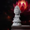 Three-quarter view of the small lotus-seated Guanyin with a red lotus in the background