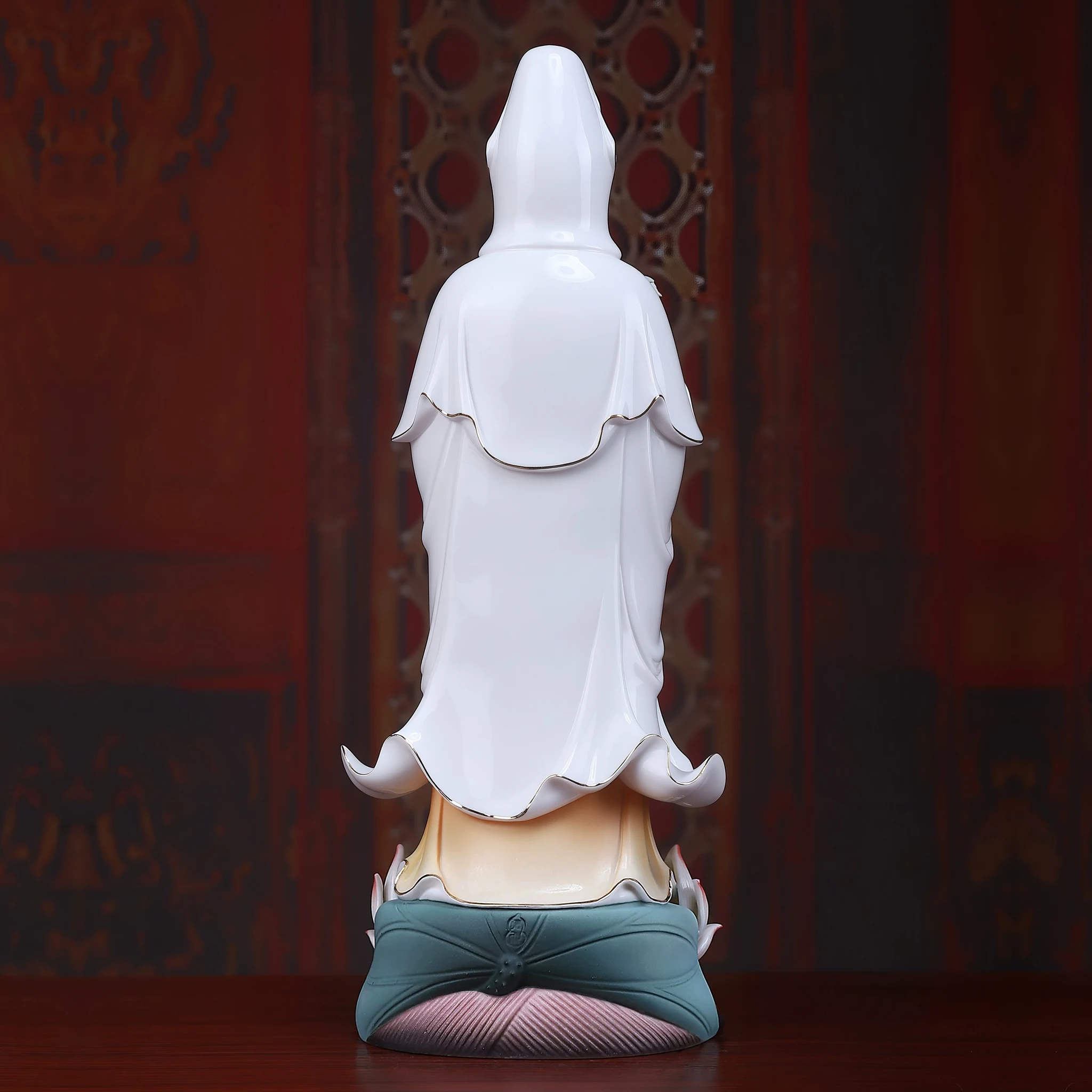 Back view of a painted porcelain Guanyin statue showing white robe folds and the rear of the lotus pedestal