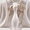 Slender vase and sculpted leaves resting below the joined palms of the 29.5 cm (11.6 in) white porcelain Guanyin