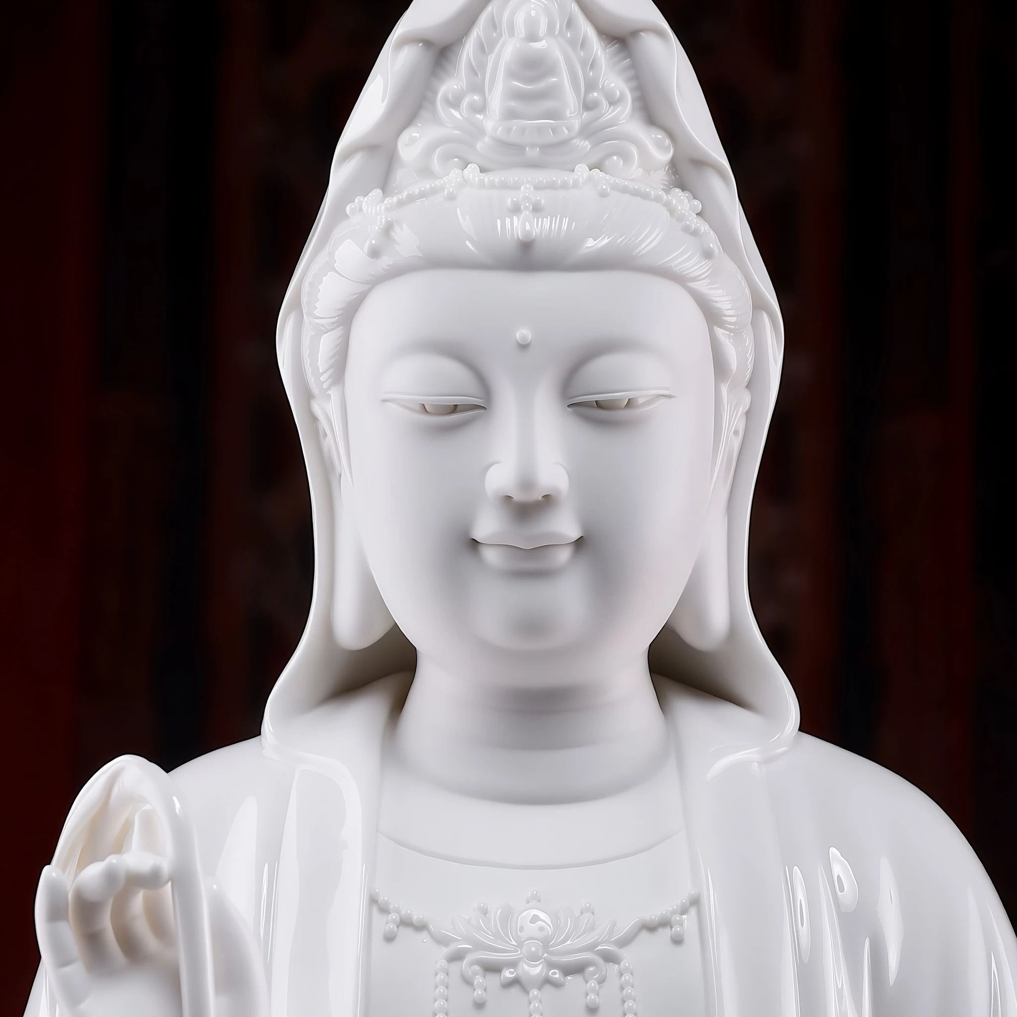 Close-up of the white Quanlian Guanyin statue, showing the face, seated figure in the crown and necklace