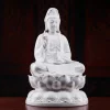 Three-quarter view of the white Quanlian Kuan Yin statue, showing the raised hand, vase, robe folds and rounded lotus pedestal
