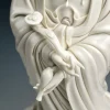 Hands holding a curved ruyi scepter and small vase on the white Guanyin statue