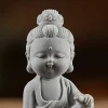 Small Kuan Yin figurine detail showing rounded cheeks, closed eyes, crown and robe folds