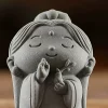 Mini Kuan Yin detail showing closed eyes, a small smile, raised fingers, vase and leafy sprig
