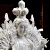 Angled close-up of Qianshou Guanyin’s face, figures above the crown and raised hands