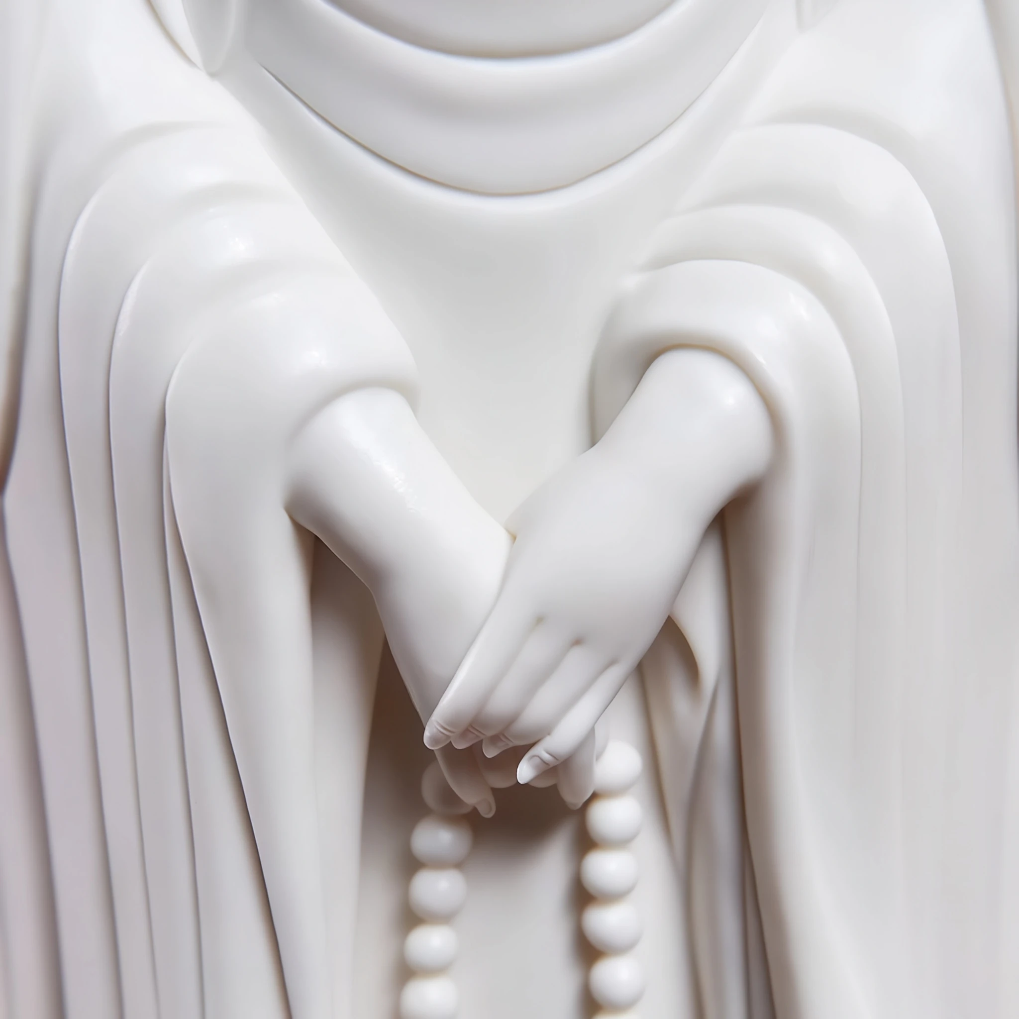 Unglazed white hands and prayer beads on the three-faced Kuan Yin sculpture