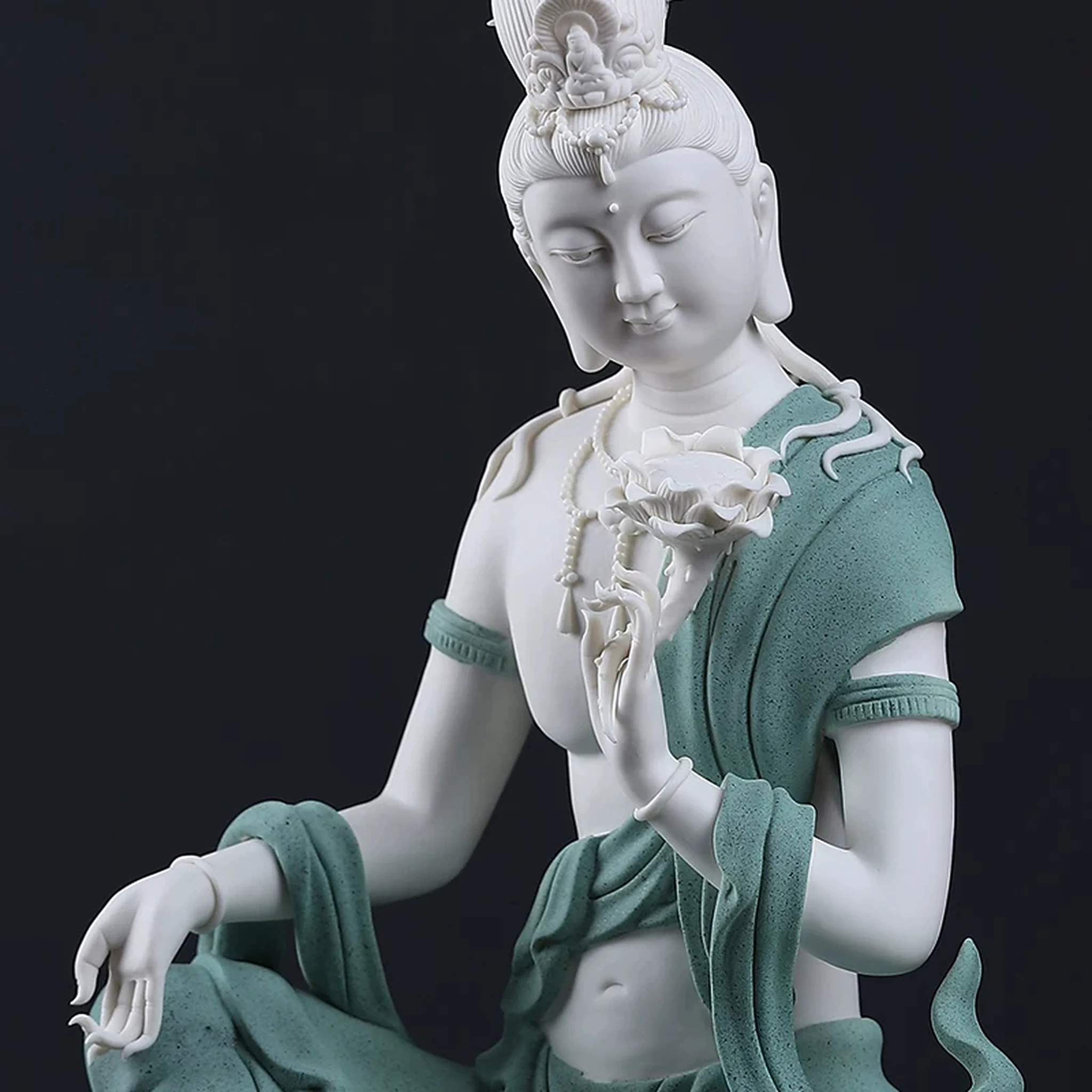 Three-quarter close-up of the teal and white Water Moon Guanyin statue with a raised knee and draped robes