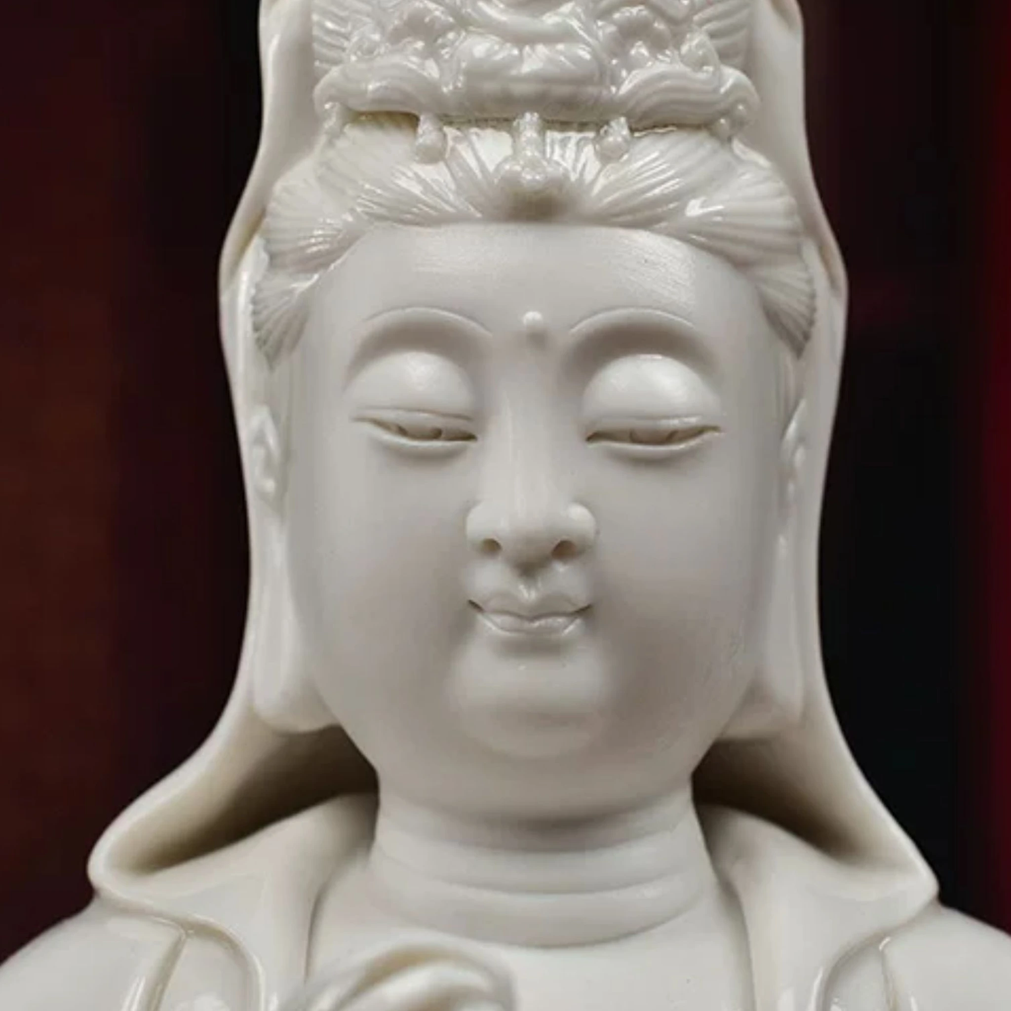 Close view of the Willow Guanyin face, lowered eyes, small smile and lower crown in glossy white ceramic