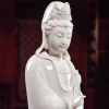 Close-up of Yangzhi Kuan Yin’s lowered eyes, small smile, raised crown details and glossy white glaze