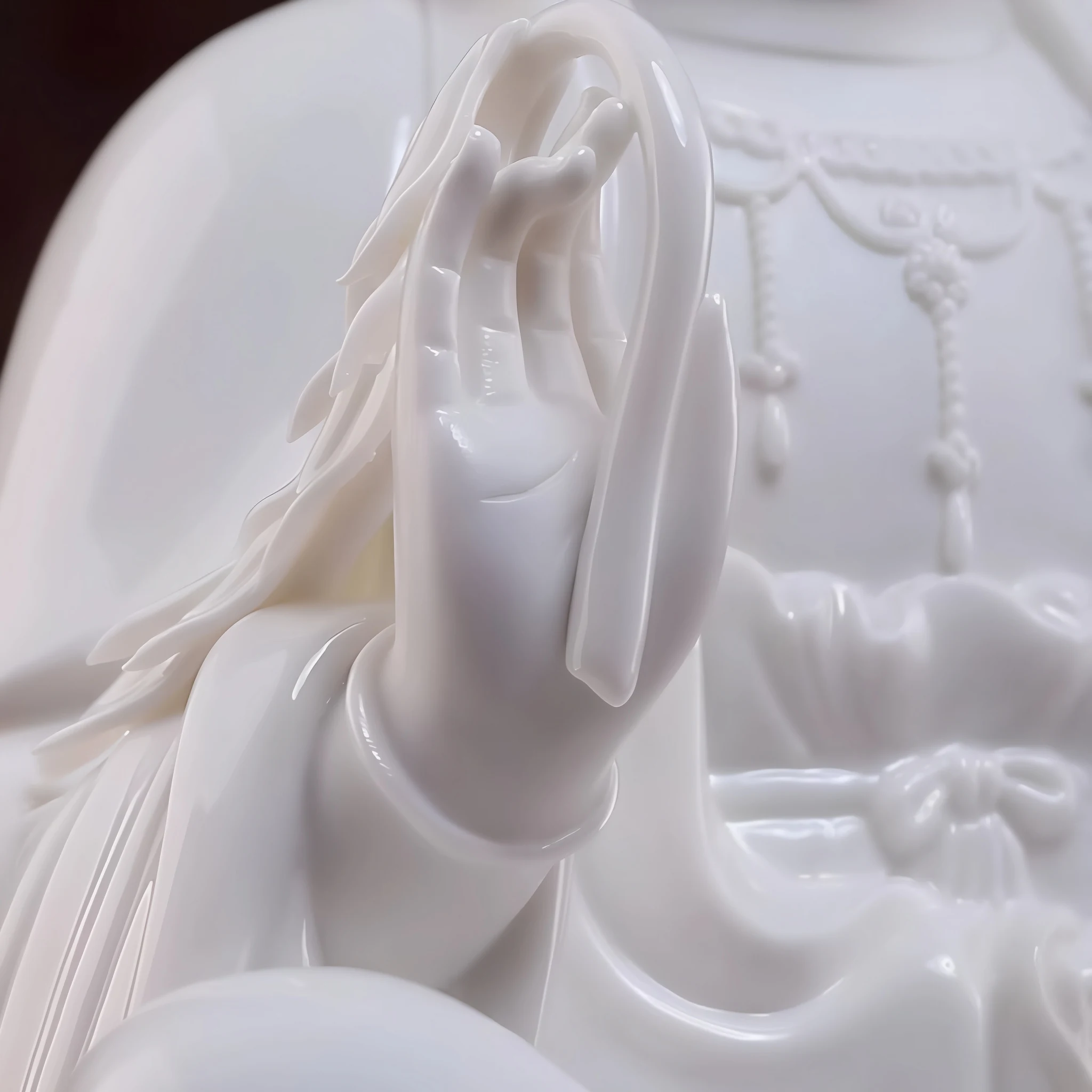 Raised hand and curved held detail on the white porcelain Zuolian Guanyin